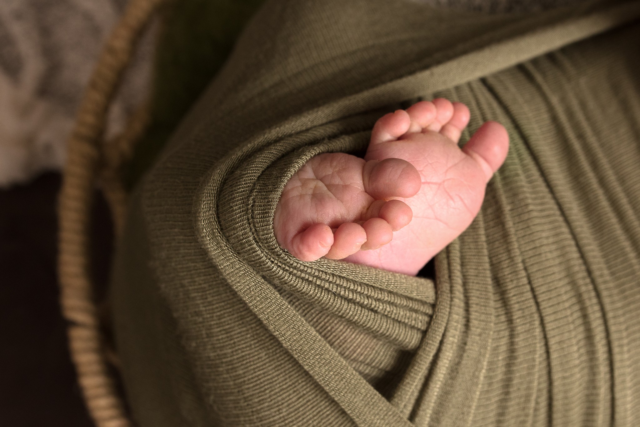Baby toes and feet exposed from a green wrap during a newborn portrait photography session in Pittsburgh, PA