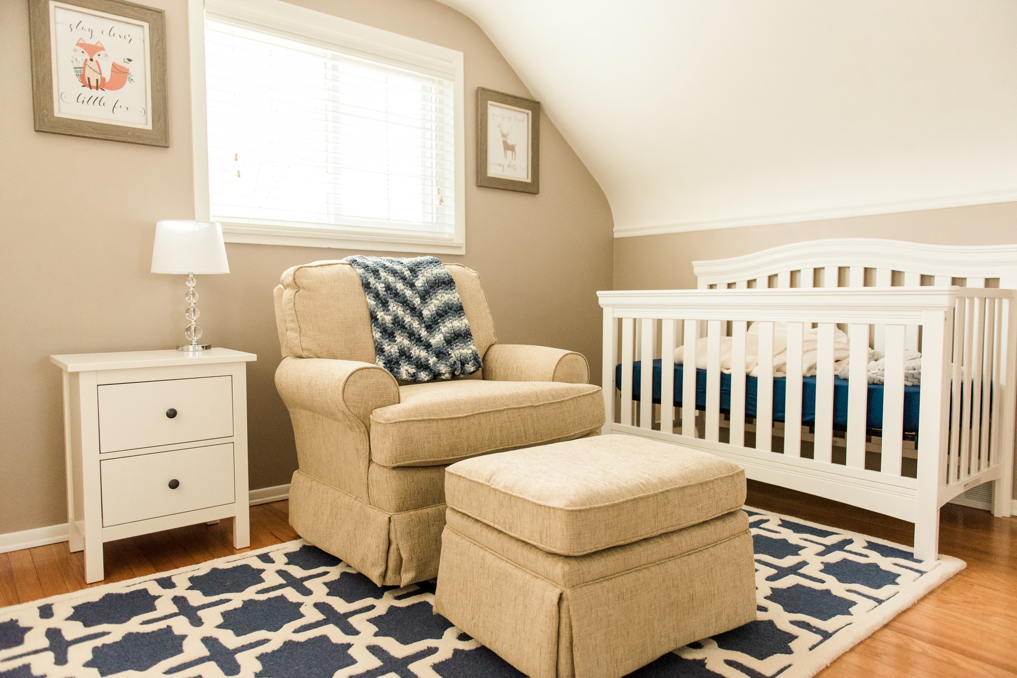 A neutral baby nursery with a white crib and blue accessories in a Pittsburgh home.