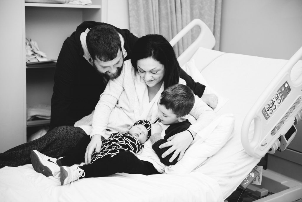 A new family of four gather on the hospital bed during their photography session in a Pittsburgh hospital.